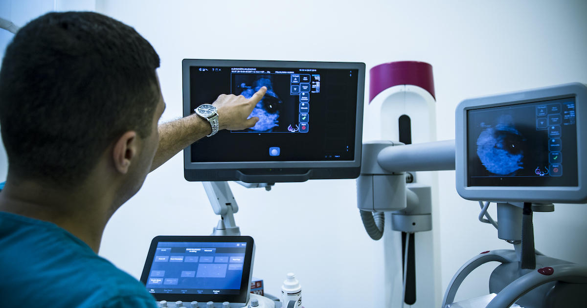 doctor points at an image on one screen at a multi-screen medical station doctor points at an image on one screen at a multi-screen medical station