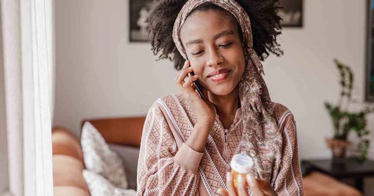 Person on the phone holding pill bottle Person on the phone holding pill bottle