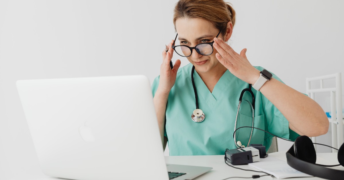 Doctor in scrubs setting up laptop for telehealth Doctor in scrubs setting up laptop for telehealth