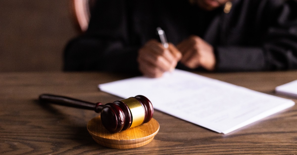 gavel on desk and judge's hands singing paper gavel on desk and judge's hands singing paper