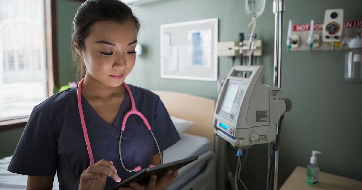 Nurse checks tablet to communicate on shift Nurse checks tablet to communicate on shift