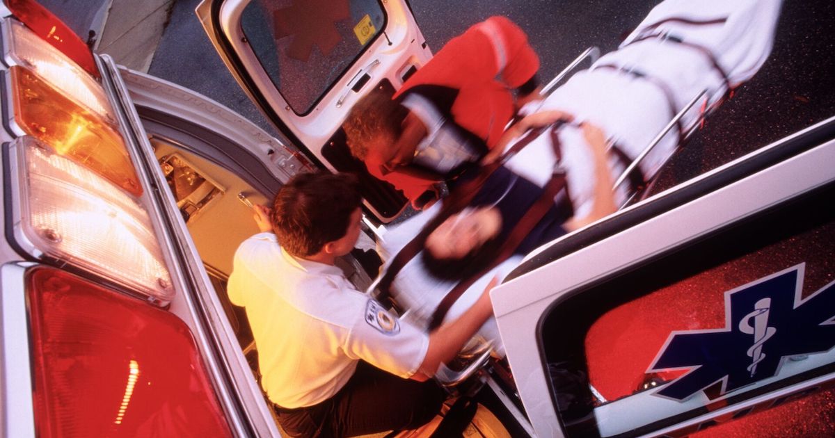 EMS technician comes out of an ambulance with patient on a stretcher EMS technician comes out of an ambulance with patient on a stretcher