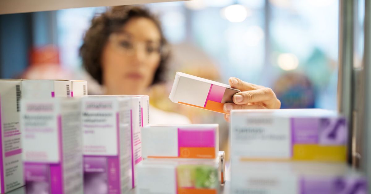 Pharmacist holds and reads a prescription drug box Pharmacist holds and reads a prescription drug box
