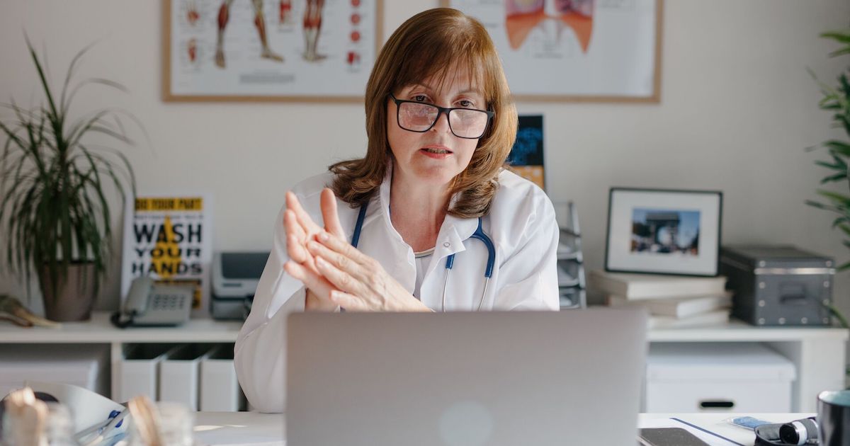 A doctor conducting an online consult in an office using a laptop