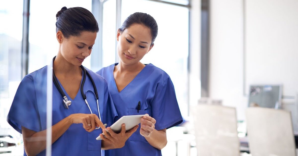Nurses reviewing a patient's record on a digital tablet Nurses reviewing a patient's record on a digital tablet