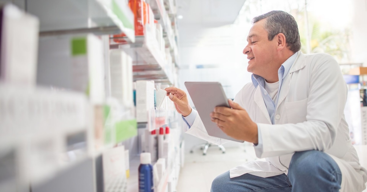 A pharmacist using a digital tablet to do an inventory.