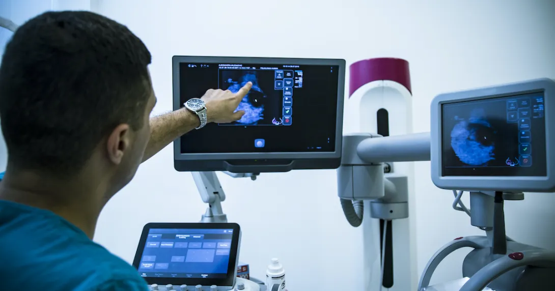 doctor points at an image on one screen at a multi-screen medical station doctor points at an image on one screen at a multi-screen medical station