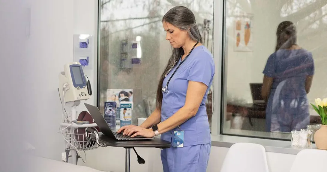 Healthcare worker using laptop in hospital room Healthcare worker using laptop in hospital room