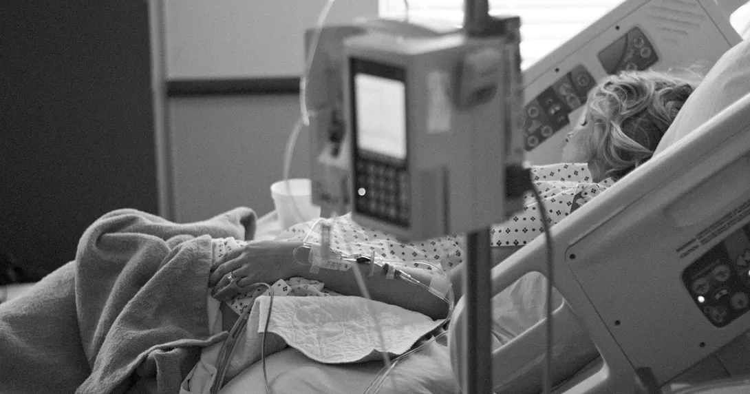 Woman asleep in hospital bed with IV in foreground Woman asleep in hospital bed with IV in foreground